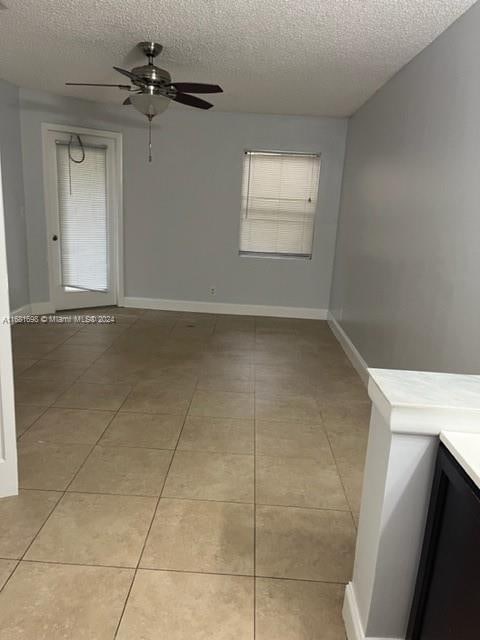 tiled spare room featuring a textured ceiling and ceiling fan