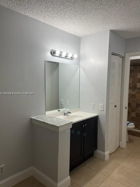 bathroom featuring vanity, toilet, a textured ceiling, and tile patterned flooring