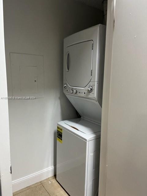 washroom featuring light tile patterned flooring, electric panel, and stacked washer and dryer