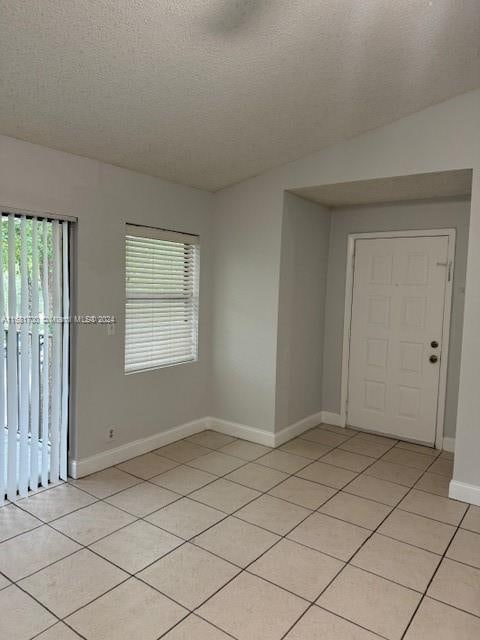 tiled empty room with a textured ceiling