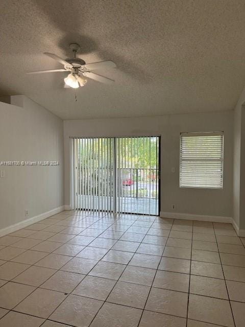 tiled spare room featuring a textured ceiling, a healthy amount of sunlight, and ceiling fan