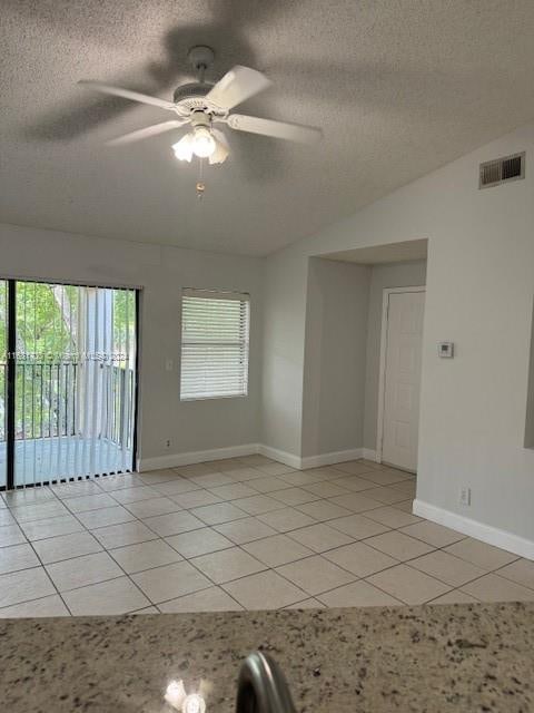 tiled spare room featuring ceiling fan, a textured ceiling, and lofted ceiling