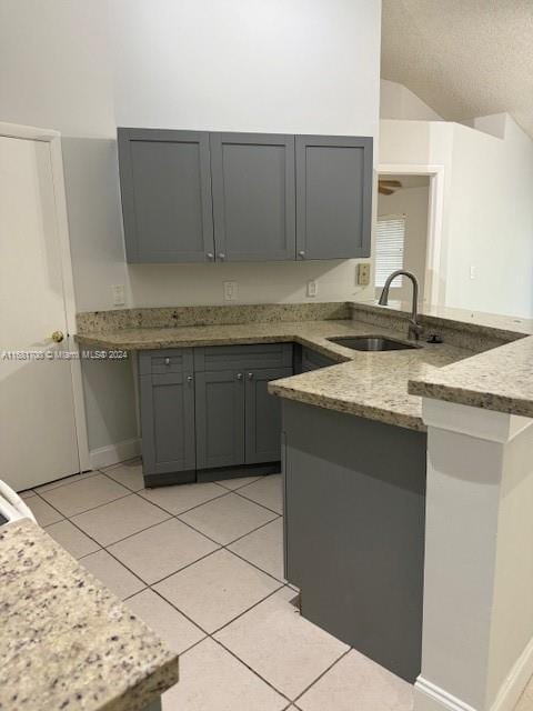 kitchen featuring sink, kitchen peninsula, gray cabinetry, and light tile patterned floors