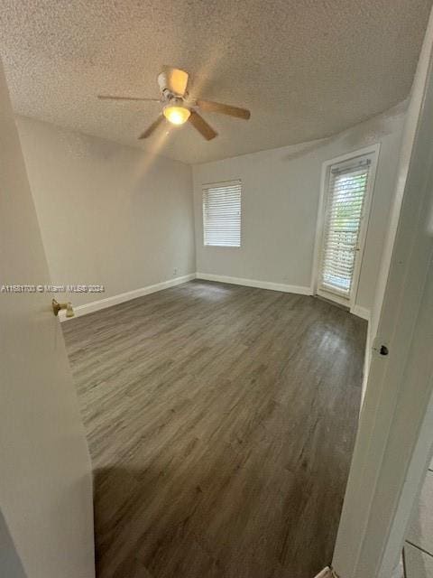 empty room with a wealth of natural light, ceiling fan, a textured ceiling, and dark hardwood / wood-style flooring