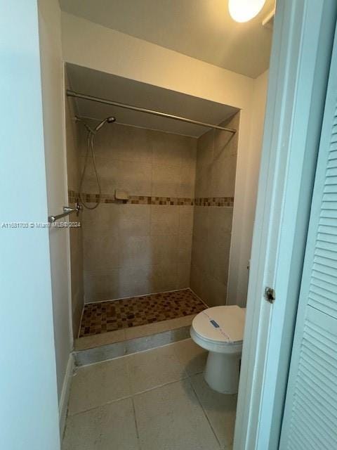 bathroom with toilet, tile patterned floors, and tiled shower