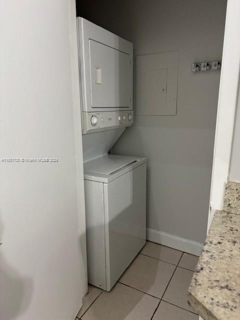 laundry room with stacked washer / dryer and light tile patterned floors