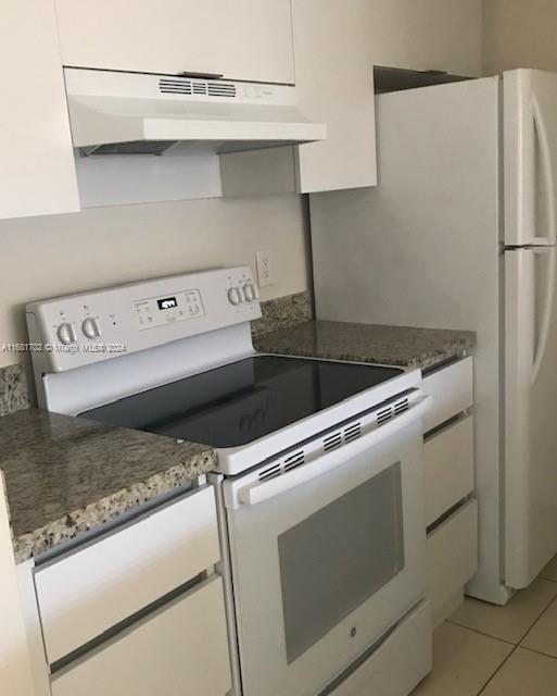 10477 NW 7th St Unit 104, Pembroke Pines, FL 33026 - kitchen with electric range, under cabinet range hood, white cabinets, light tile patterned floors, and light stone countertops