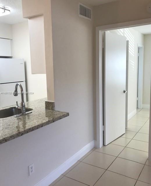 10477 NW 7th St Unit 104, Pembroke Pines, FL 33026 - kitchen with freestanding refrigerator, stone countertops, and light tile patterned floors