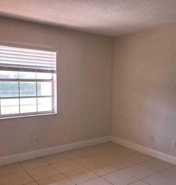 tiled spare room featuring a textured ceiling