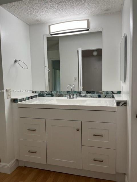 bathroom featuring hardwood / wood-style flooring, vanity, and a textured ceiling