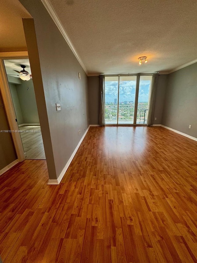 spare room with hardwood / wood-style floors, crown molding, a textured ceiling, and floor to ceiling windows