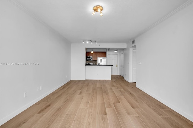 unfurnished living room with crown molding, visible vents, baseboards, light wood finished floors, and track lighting