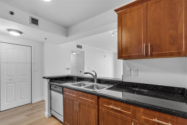 kitchen with a sink, visible vents, light wood-style floors, dishwasher, and dark stone countertops