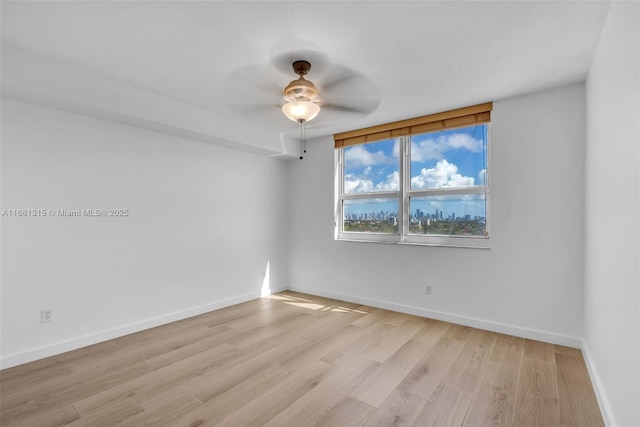 spare room with light wood-style flooring, baseboards, and a ceiling fan