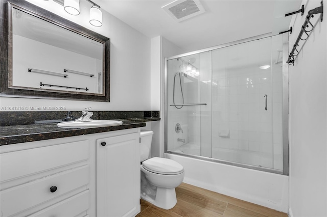 full bathroom featuring visible vents, toilet, enclosed tub / shower combo, wood finished floors, and vanity