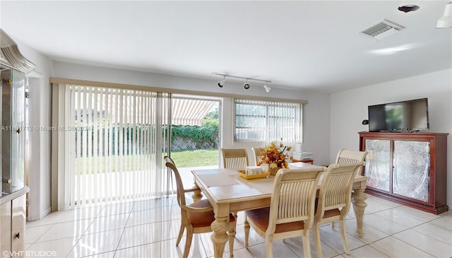 dining space with track lighting and light tile patterned floors