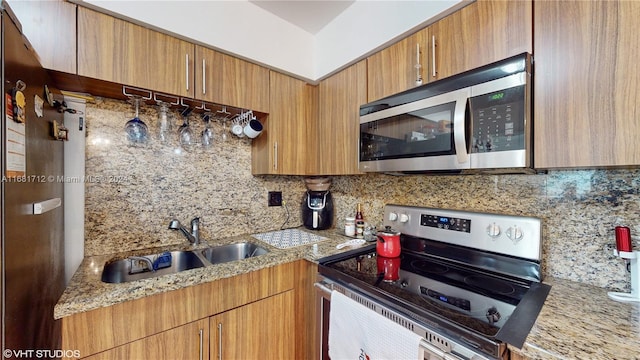 kitchen with sink, light stone countertops, stainless steel appliances, and backsplash