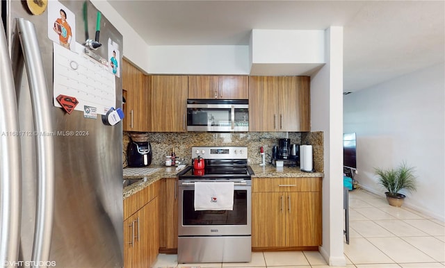 kitchen with light stone countertops, stainless steel appliances, decorative backsplash, and light tile patterned flooring