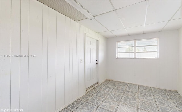 spare room featuring wooden walls and a paneled ceiling