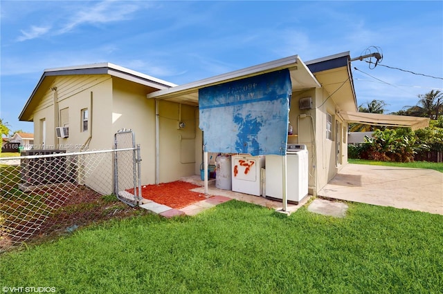 rear view of house featuring a carport, a lawn, cooling unit, and washer and dryer