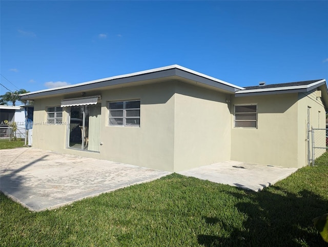 back of property with a yard and a patio