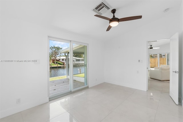 tiled spare room featuring a water view, ceiling fan, and plenty of natural light