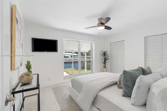 bedroom featuring multiple closets, ceiling fan, and light tile patterned floors