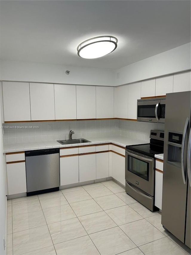 kitchen featuring decorative backsplash, white cabinetry, sink, and stainless steel appliances