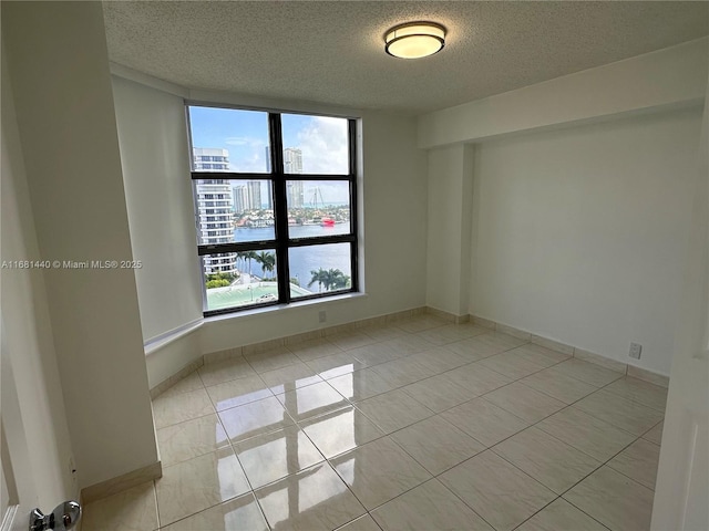 empty room featuring light tile patterned floors, a textured ceiling, and a healthy amount of sunlight