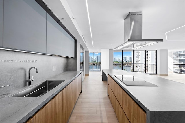 kitchen featuring island range hood, sink, backsplash, floor to ceiling windows, and a water view