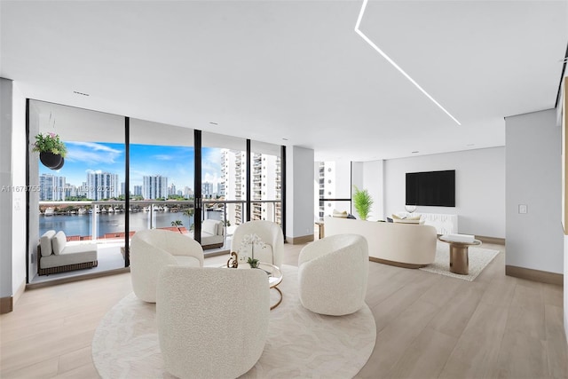 living area with expansive windows, baseboards, and light wood-style flooring