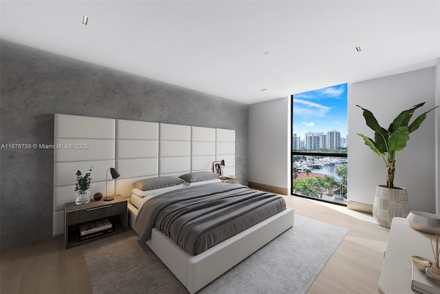 bedroom with expansive windows and light hardwood / wood-style flooring