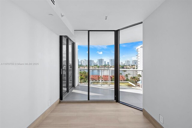 spare room with a water view, a wall of windows, and light hardwood / wood-style floors