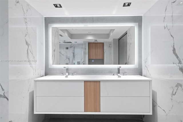 bathroom with vanity, a tray ceiling, tile walls, and walk in shower