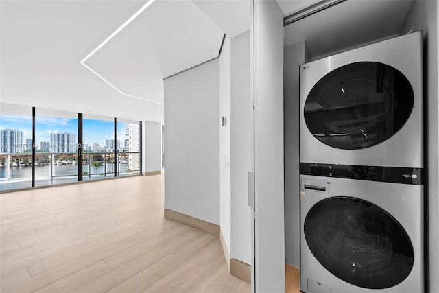 laundry area with a water view, stacked washer and clothes dryer, and light hardwood / wood-style flooring