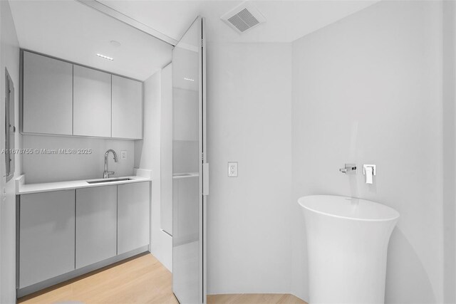 bathroom featuring vanity, a tub to relax in, and wood-type flooring