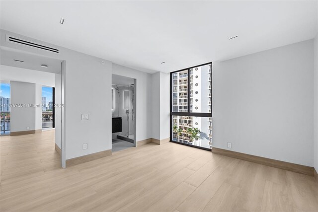 unfurnished room featuring floor to ceiling windows and light wood-type flooring