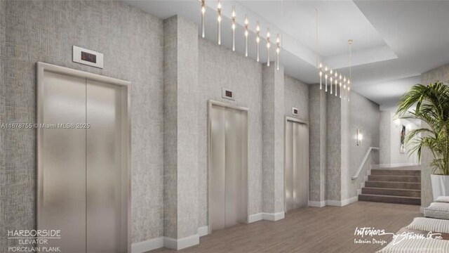 stairs featuring a tray ceiling, wood-type flooring, elevator, and a high ceiling