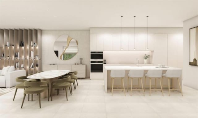 kitchen featuring an island with sink, sink, pendant lighting, white cabinets, and black double oven