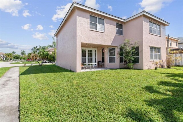 back of property with a yard and a patio area