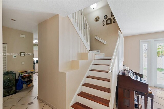 stairway with a textured ceiling and tile patterned flooring