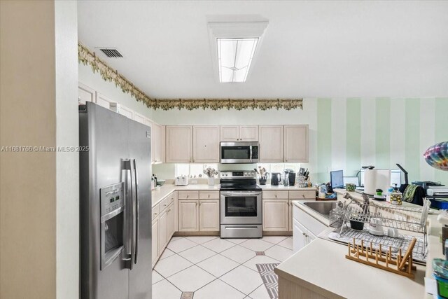 kitchen with light brown cabinetry, appliances with stainless steel finishes, and sink