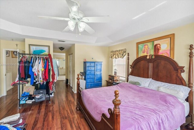 bedroom featuring dark hardwood / wood-style floors, a tray ceiling, and ceiling fan