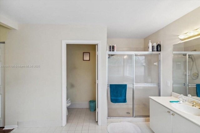 bathroom with vanity, a shower with shower door, toilet, and tile patterned floors