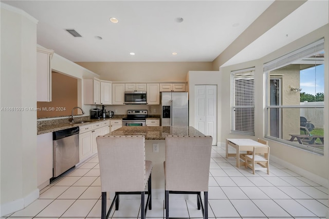 kitchen featuring appliances with stainless steel finishes, a center island, sink, and light stone counters