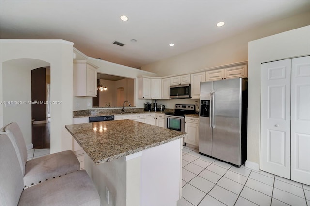 kitchen with light stone countertops, sink, a kitchen island, stainless steel appliances, and a breakfast bar area