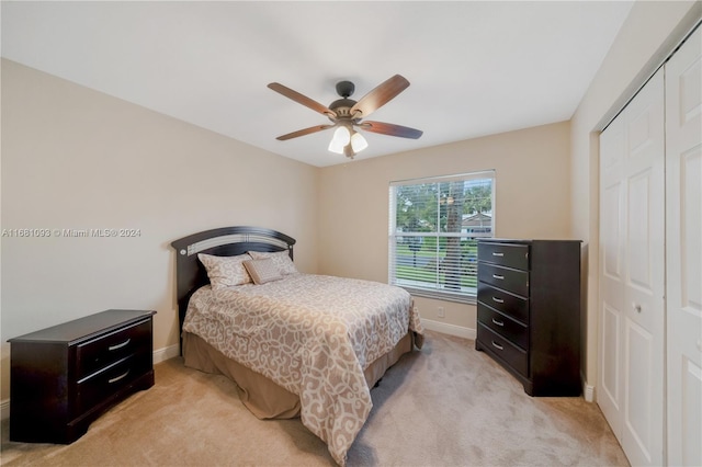 bedroom with a closet, ceiling fan, and light colored carpet