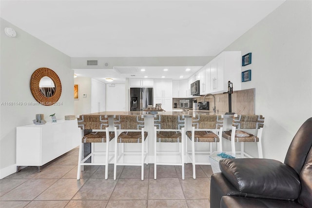 kitchen featuring appliances with stainless steel finishes, kitchen peninsula, white cabinetry, and a breakfast bar area