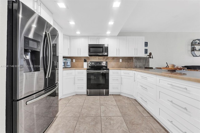 kitchen with appliances with stainless steel finishes, white cabinetry, tasteful backsplash, and light tile patterned flooring