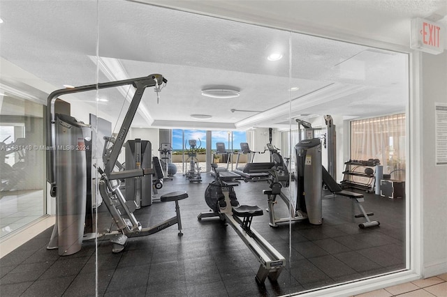 workout area with a wall of windows, crown molding, a textured ceiling, and a raised ceiling